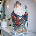Decorative Santa Claus figurine with a winter scene design on a white surface.